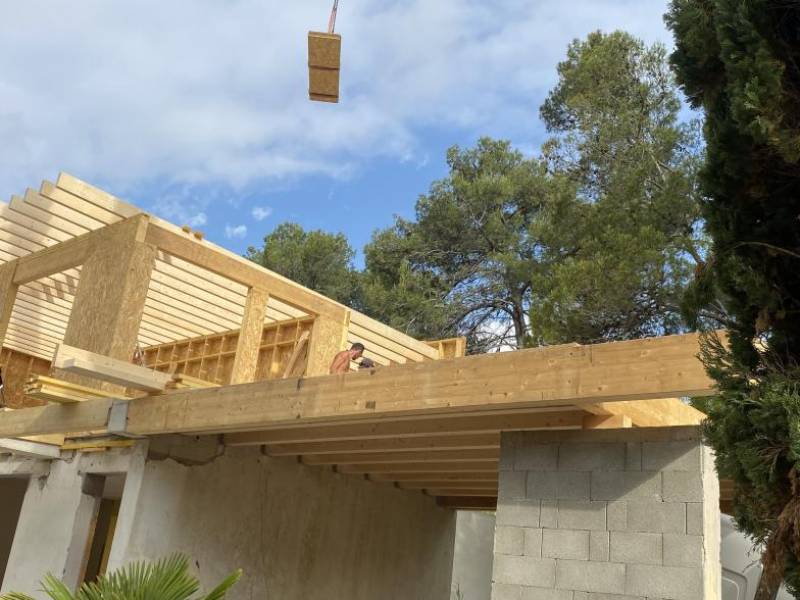 Équipe de charpentiers en action sur la surélévation d'une maison en ossature bois